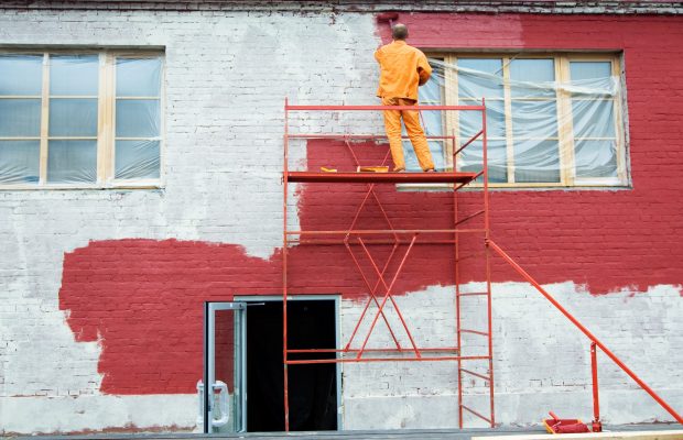 Man painting a brick wall in red